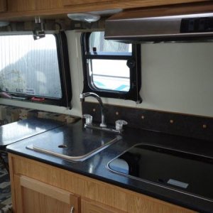 Black counter top, stainless hood, and SMEV stove.